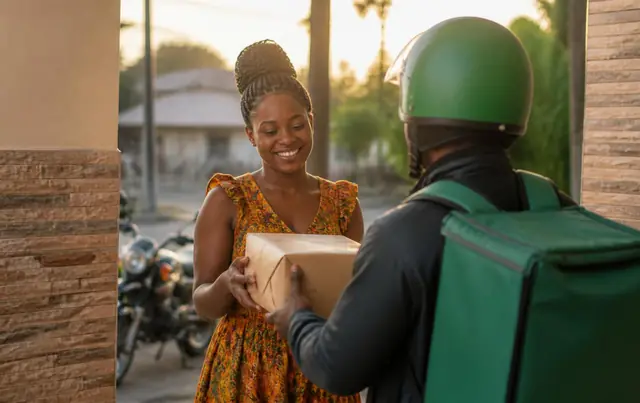 Livreur Babana remettant un colis à une cliente lors d'une livraison AKAMBA